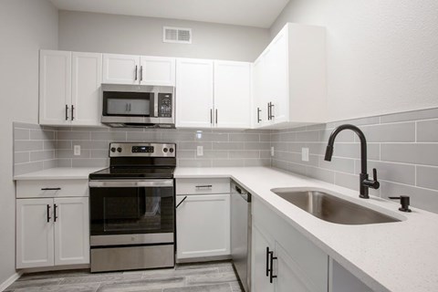 A kitchen with white cabinets and a black stove top oven.