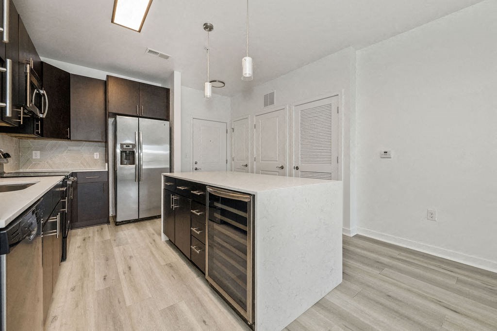 A kitchen with a white counter top and wooden floors.