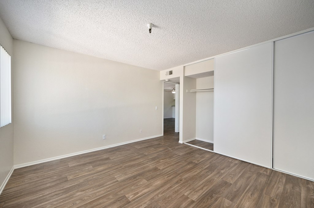 a bedroom with wood floors and a closet