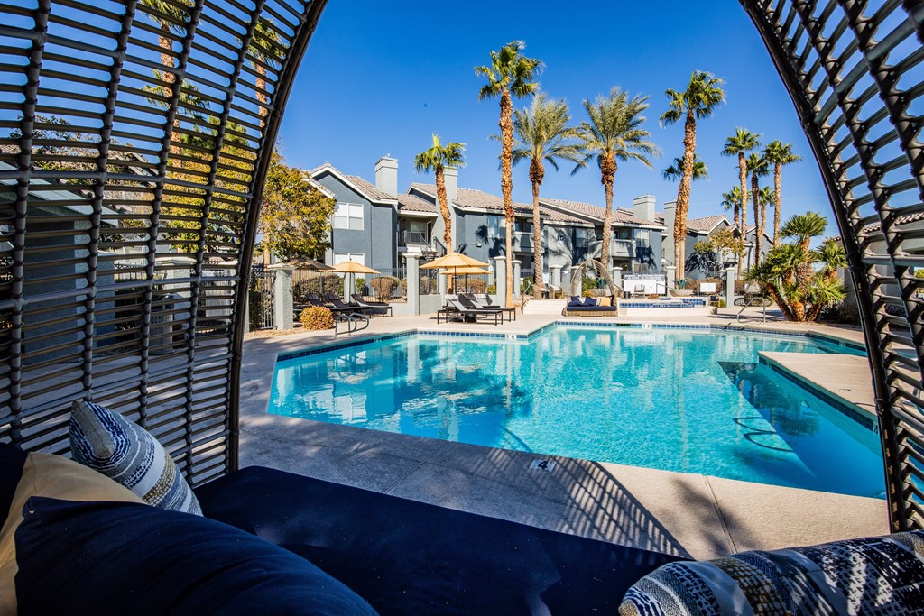 A pool surrounded by palm trees and a patio area.