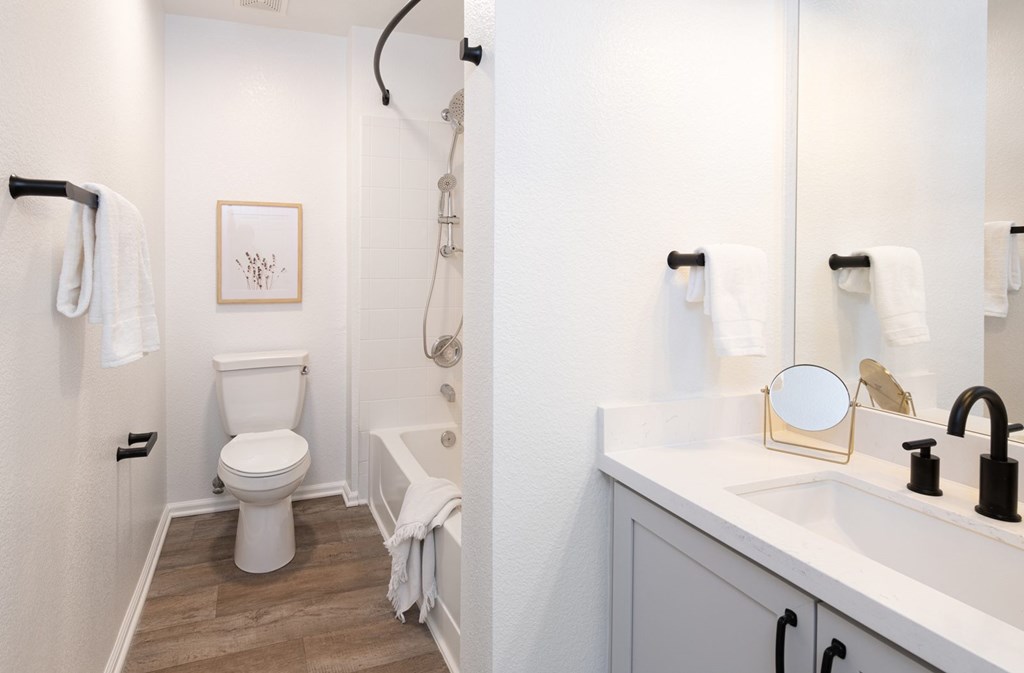 A white toilet is in a small bathroom with a white sink.