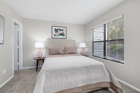 A bedroom with a large bed and two lamps.
