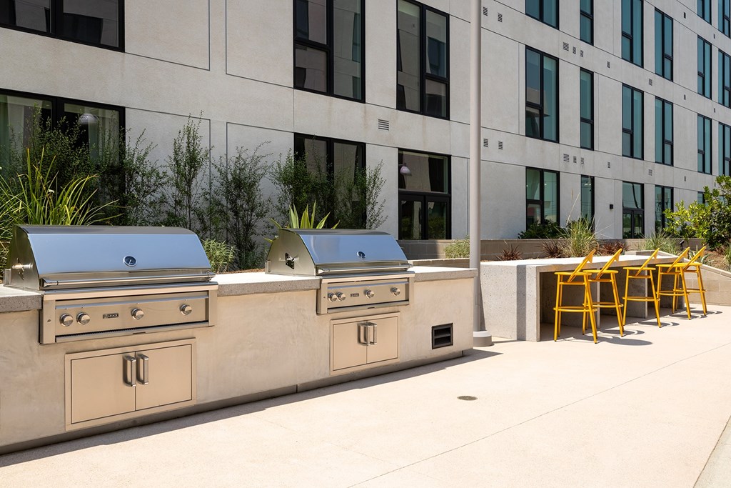 A row of outdoor BBQs are lined up on a patio.