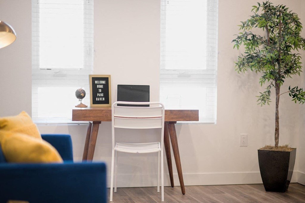 a desk with a laptop and a plant in a living room