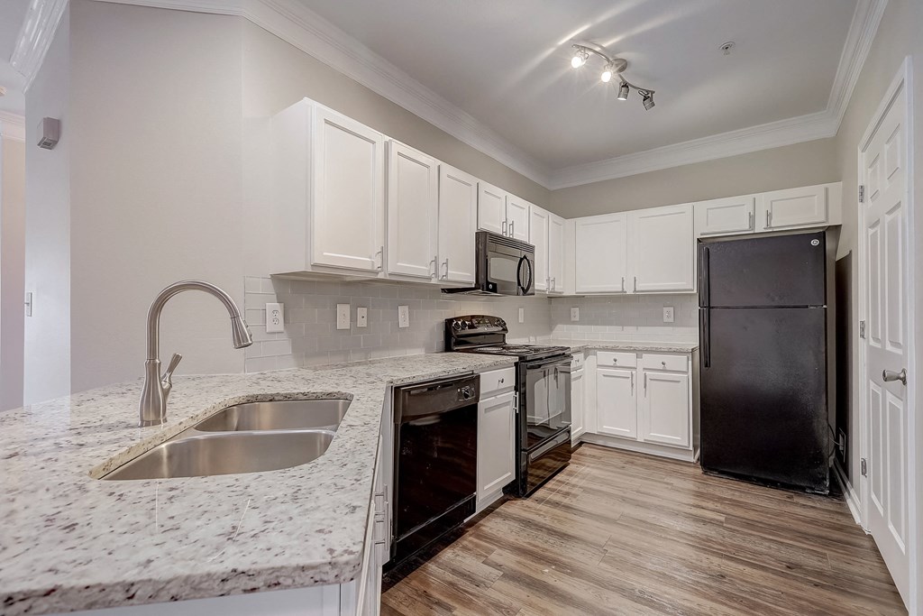 a kitchen with white cabinets and black appliances