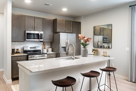 a kitchen with a large island with stools and stainless steel appliances