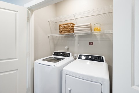 a washer and dryer in a small laundry room with a shelf above them