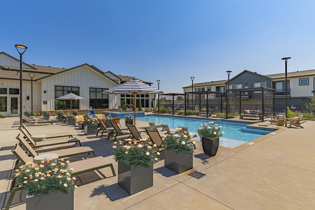 A pool area with sun loungers and a building in the background.
