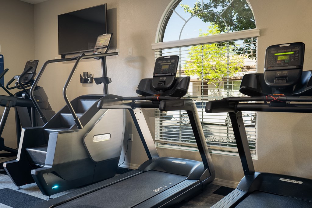 two treadmills and a tv in a gym with a window