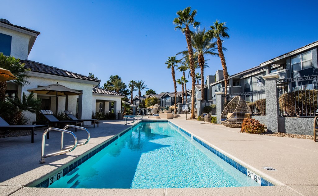 A swimming pool surrounded by palm trees and buildings.