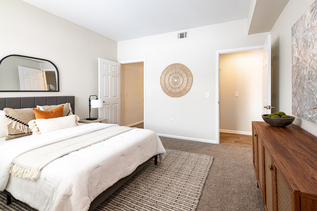 A bedroom with a large bed and a wooden cabinet.