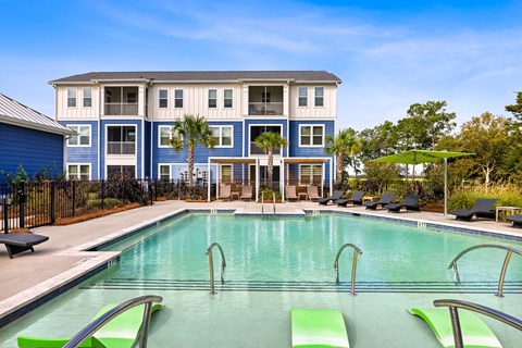 A large blue and white building with a pool in front.
