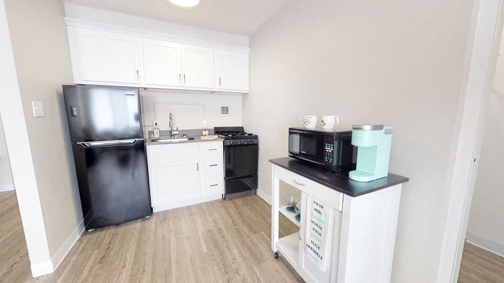 a kitchen with white cabinets and black appliances