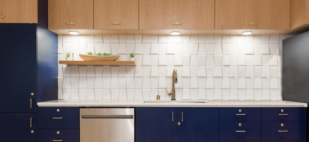 a kitchen with white tiles and navy cabinets