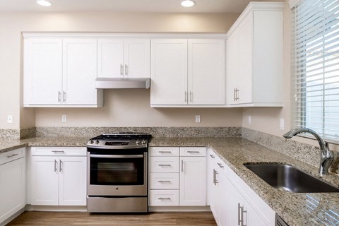 a kitchen with white cabinets and a granite counter top