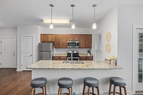 A kitchen with a granite countertop and bar stools.