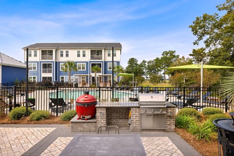 A red grill is in front of a building with a pool.