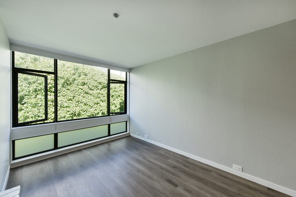 an empty living room with a large window and wood flooring