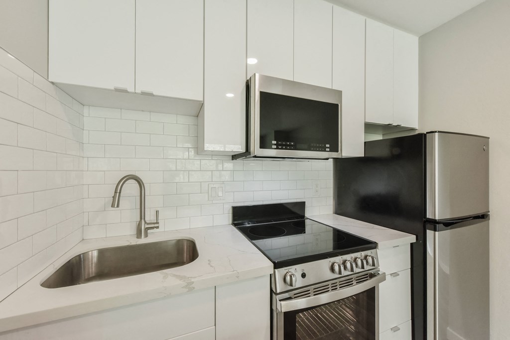 a kitchen with white cabinets and a sink and a refrigerator