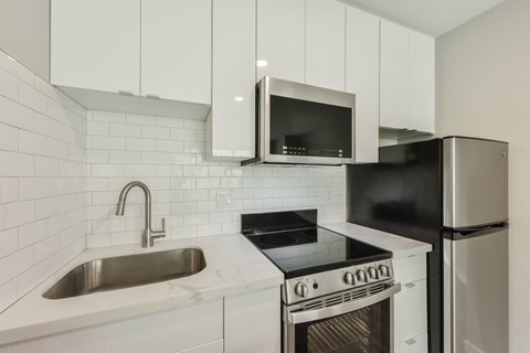 a kitchen with white cabinets and a sink and a refrigerator