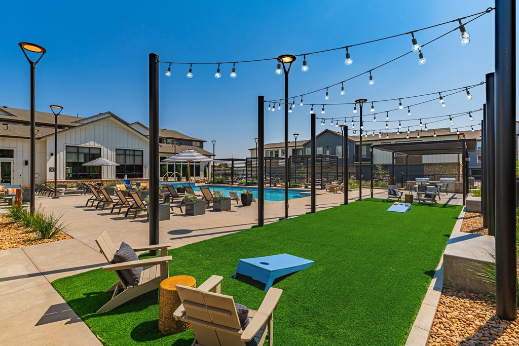 A sunny day at the poolside with lounge chairs and string lights.