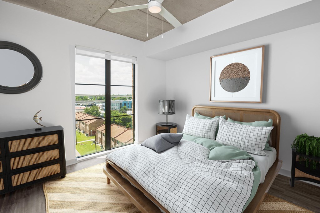 a bedroom with a large window and a bed with a comforter and pillows