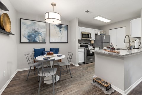 A kitchen with a table and chairs and a fridge.
