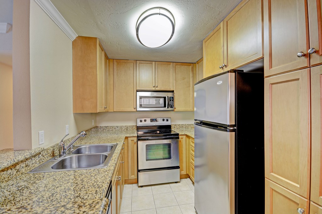 A kitchen with a refrigerator, oven, and sink.