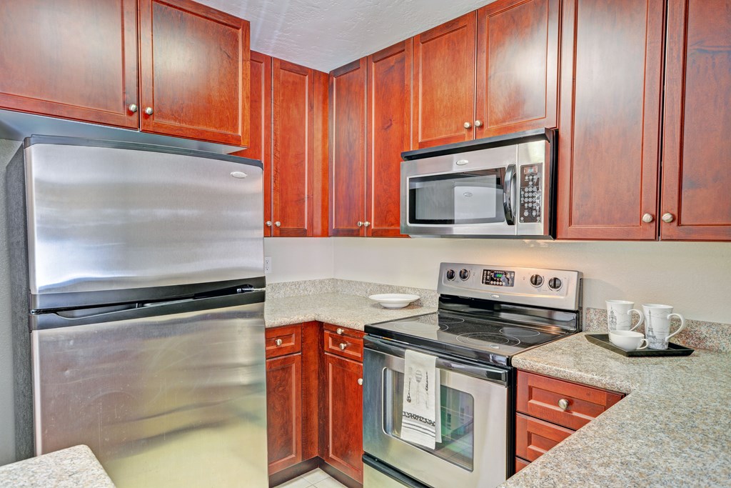 A kitchen with wooden cabinets and a stainless steel refrigerator.