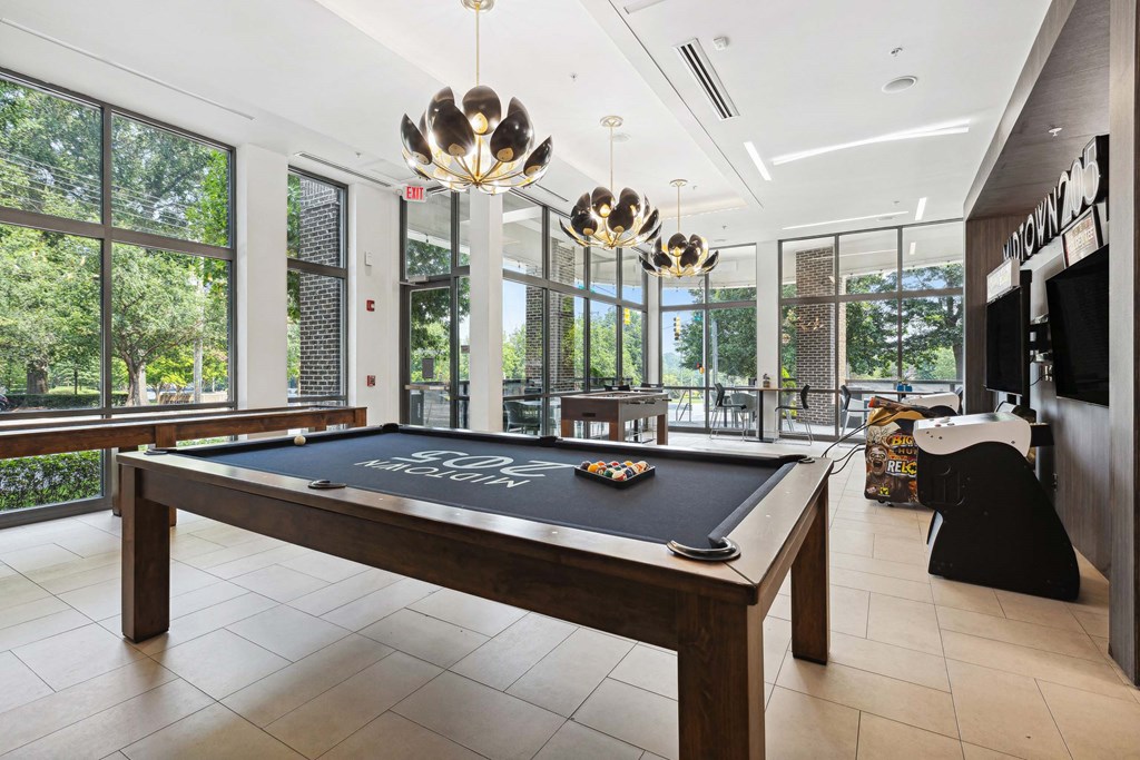 A pool table in a room with a view of trees outside the window.