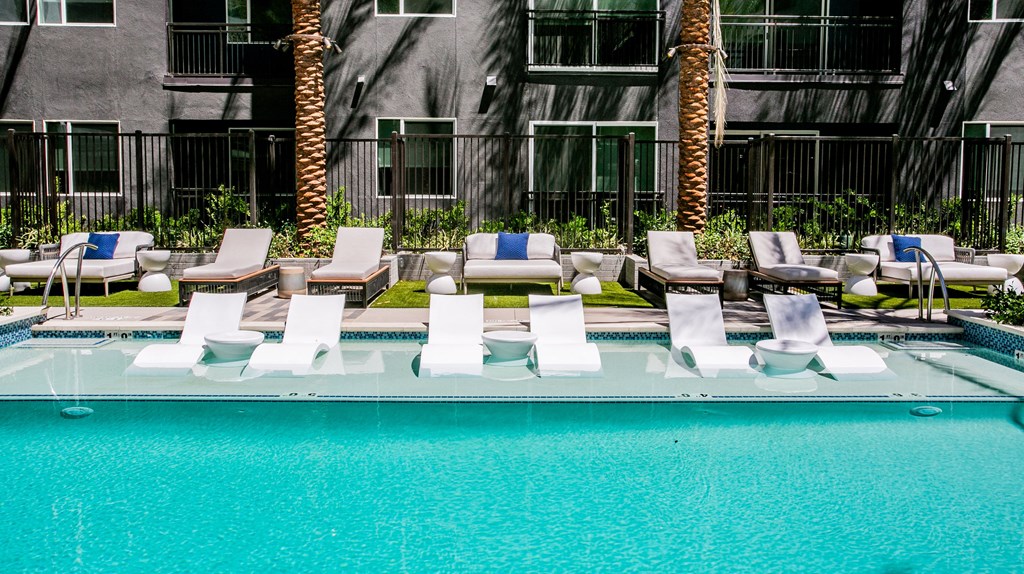 a pool with lounge chairs and palm trees in the background