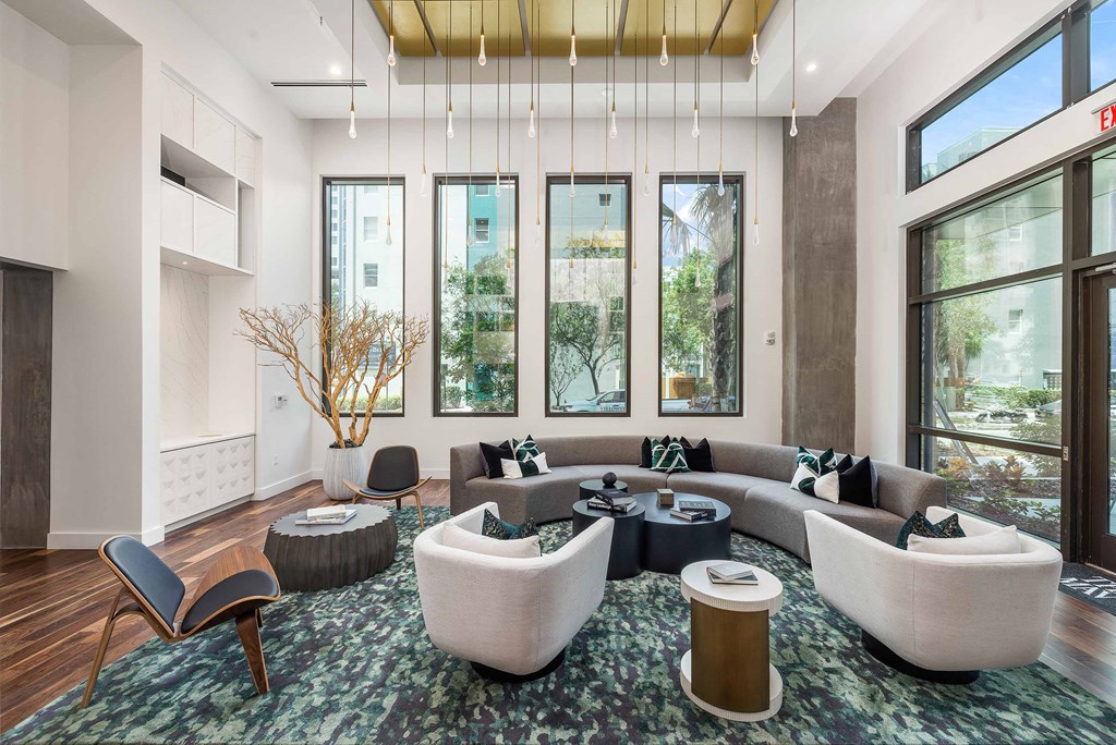 a living room with couches and chairs and large windows