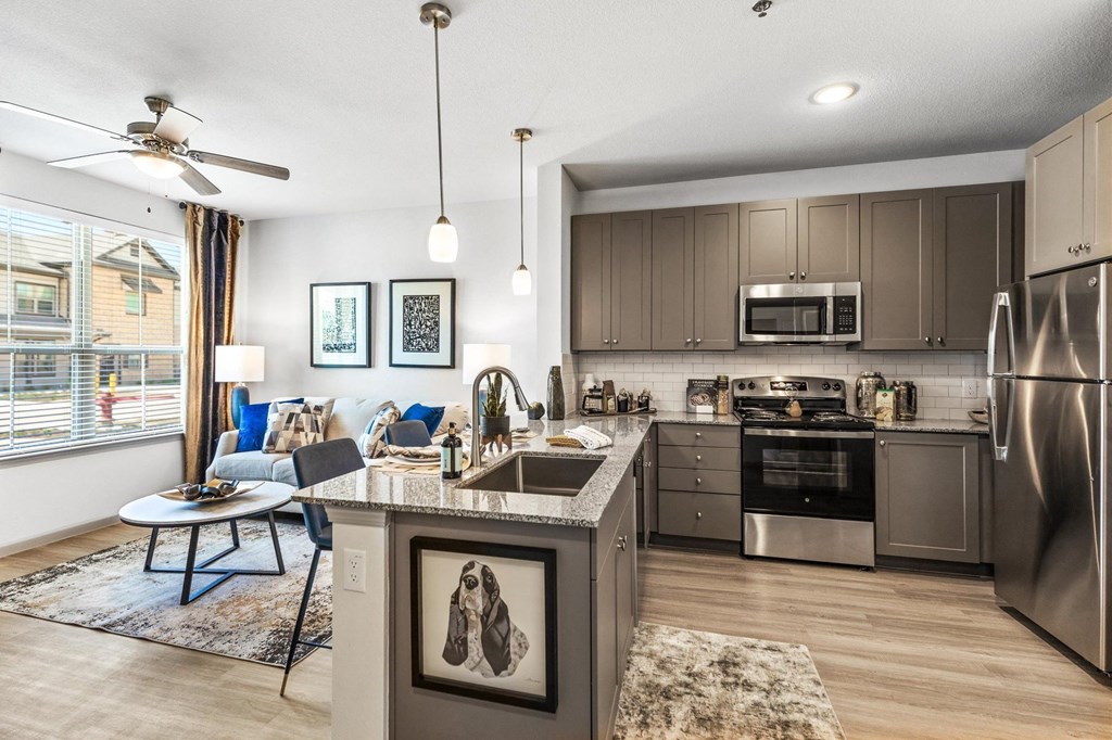 a kitchen and living room with a large window and a ceiling fan