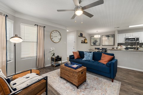 A living room with a blue couch and a ceiling fan.