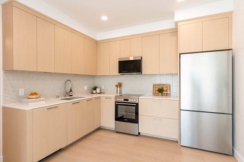 A kitchen with a refrigerator, oven, and microwave.