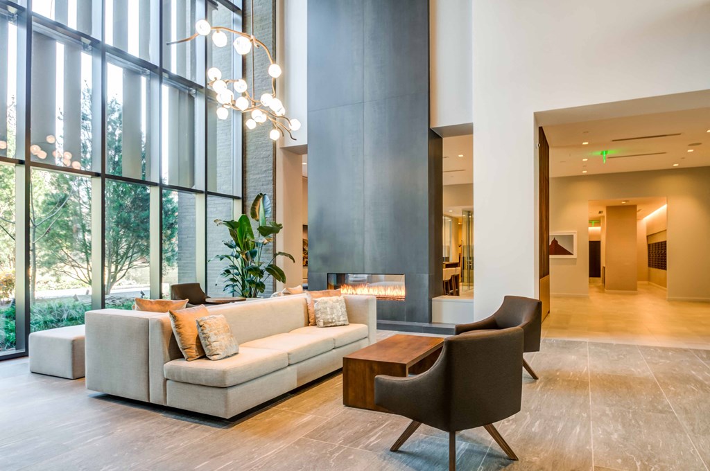 a living room with a couch and chairs and large windows