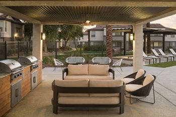 A patio with a couch, chairs, and a grill.