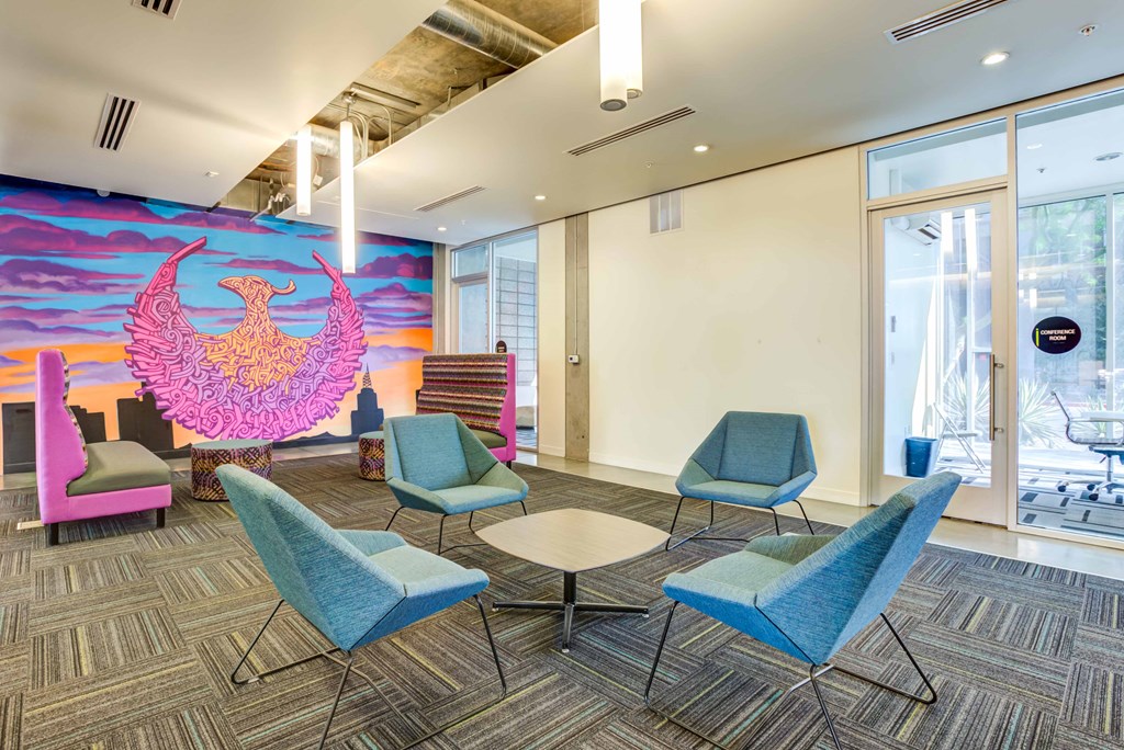 a lounge area with chairs and a mural on the wall
