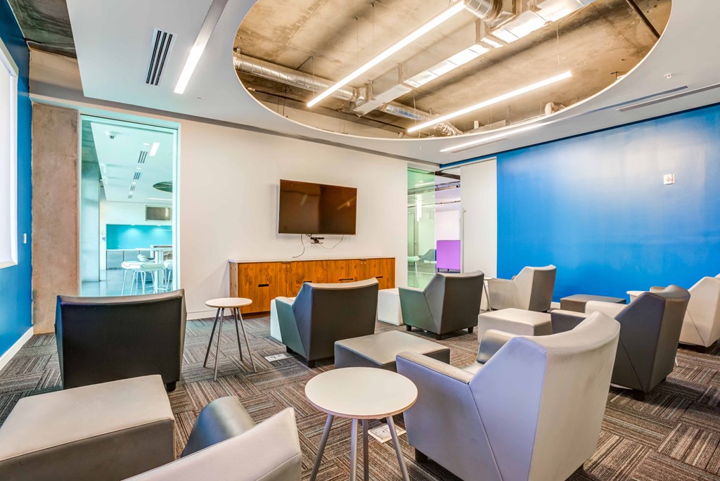 a lounge area with chairs and tables and a television