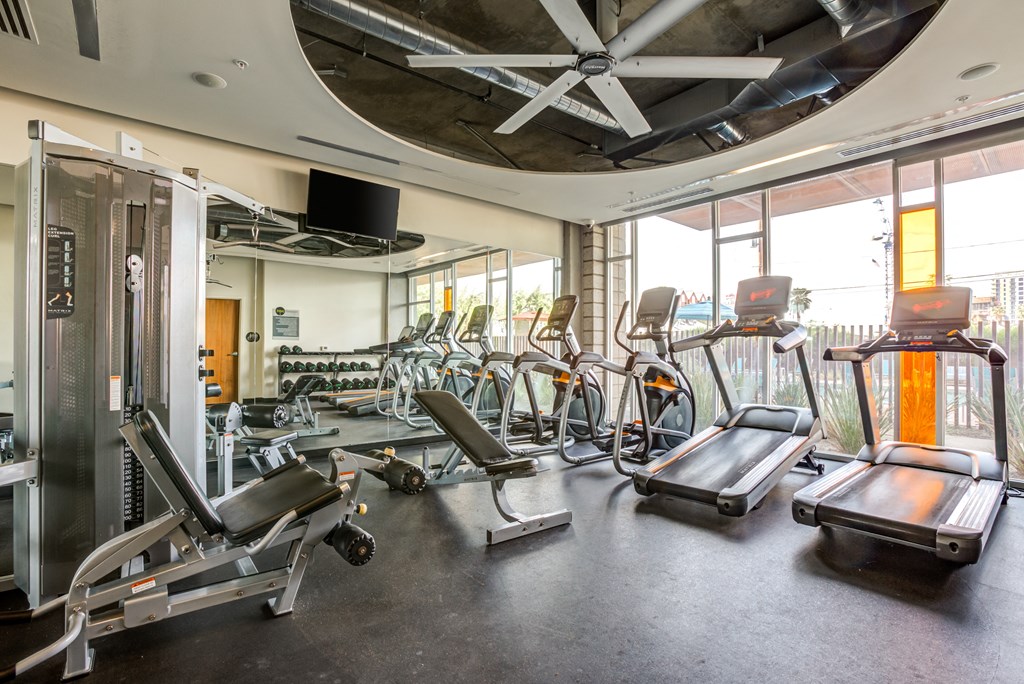 a gym with cardio equipment and windows in a building