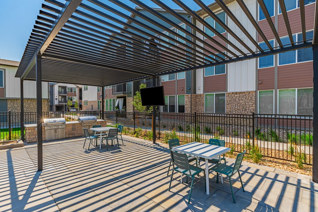 A patio with a table and chairs under a wooden pergola.