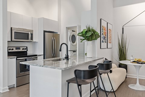 A modern kitchen with a marble countertop and stainless steel appliances.