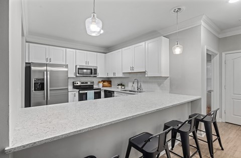 A kitchen with white cabinets and a marble countertop.