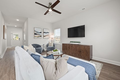 A living room with a white couch and a ceiling fan.