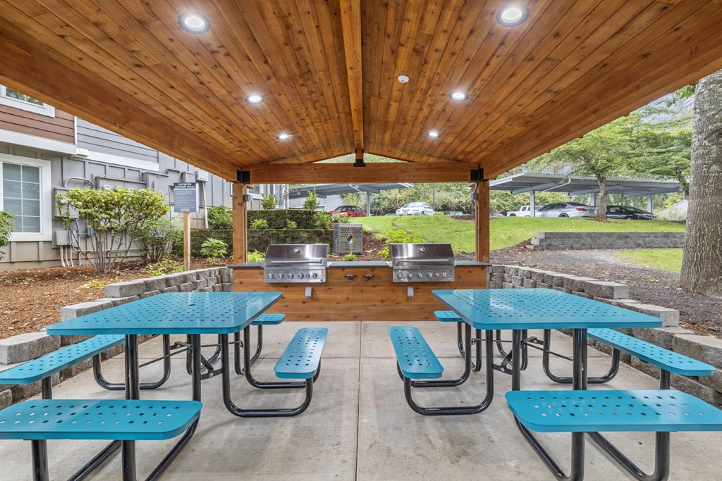 a covered patio with tables and chairs and a grill