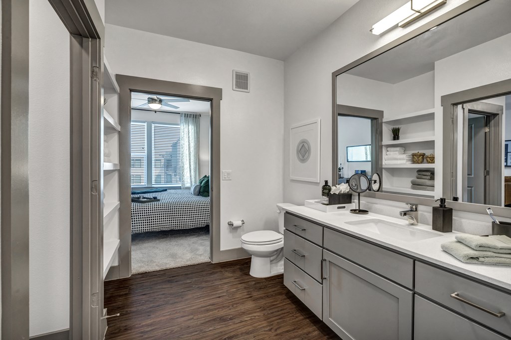 an open bathroom with a large mirror and a toilet and sink