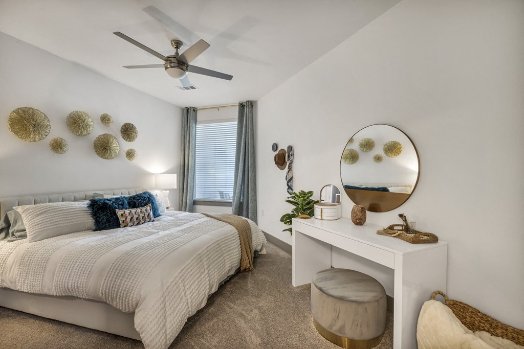 a bedroom with a bed and a mirror and a ceiling fan