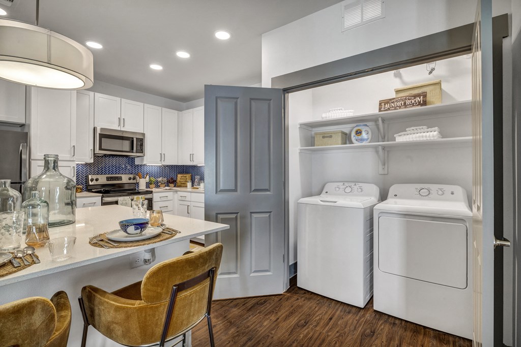 a kitchen with a washer and dryer and a table with chairs