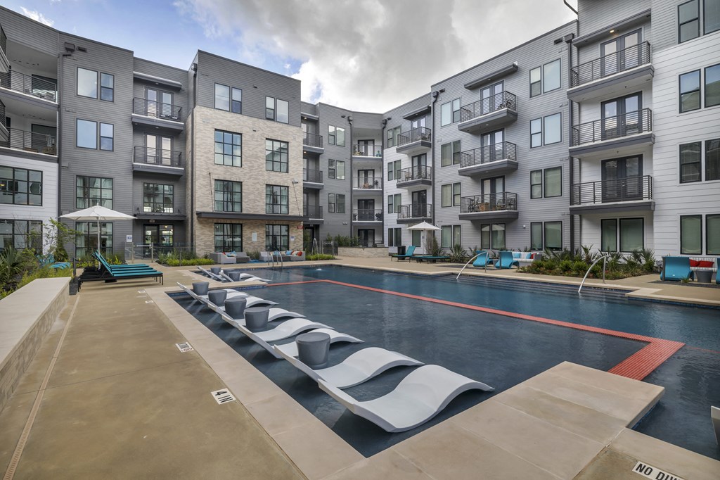 an apartment building with a pool and lounge chairs