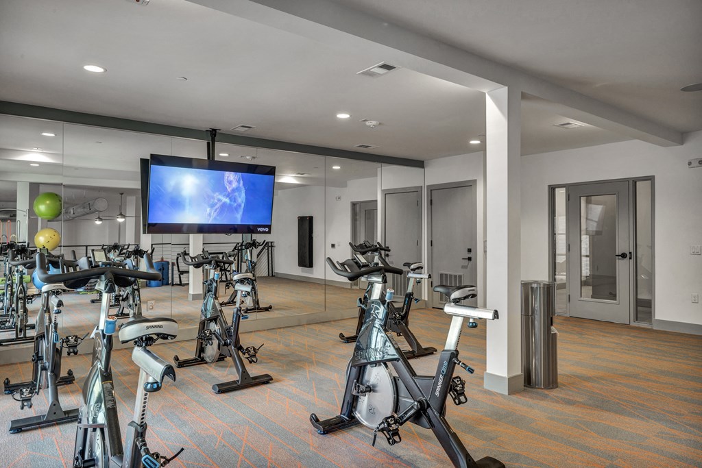 a workout room with exercise bikes and a television